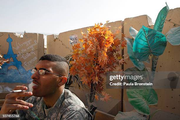 Army Private First Class Michael Shelton smokes after lunch at La Patisserie french cafe along the boardwalk at Kandahar Air Field December 8, 2010...