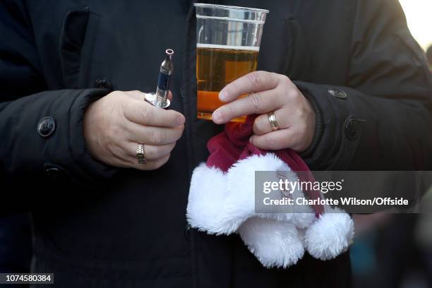 West Ham fan with a signet ring, a vape, a pint of beer and a club Christmas hat ahead of the Premier League match between West Ham United and...