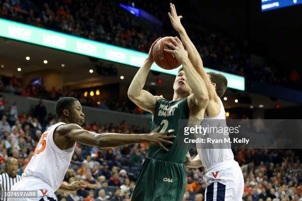 Matt Milon of the William & Mary Tribe is defended by Mamadi Diakite and Kyle Guy of the Virginia Cavaliers in the first half during a game at John...