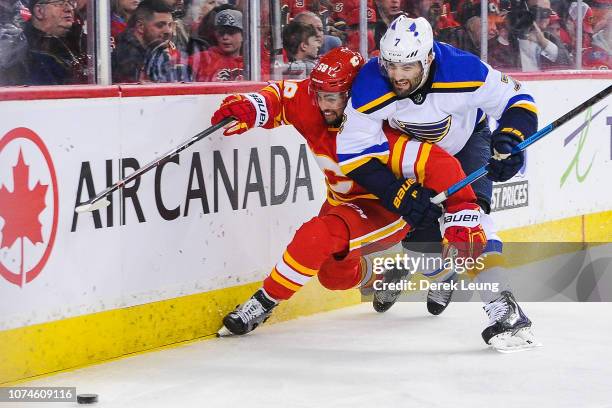 Oliver Kylington of the Calgary Flames chases the puck against Patrick Maroon of the St Louis Blues during an NHL game at Scotiabank Saddledome on...