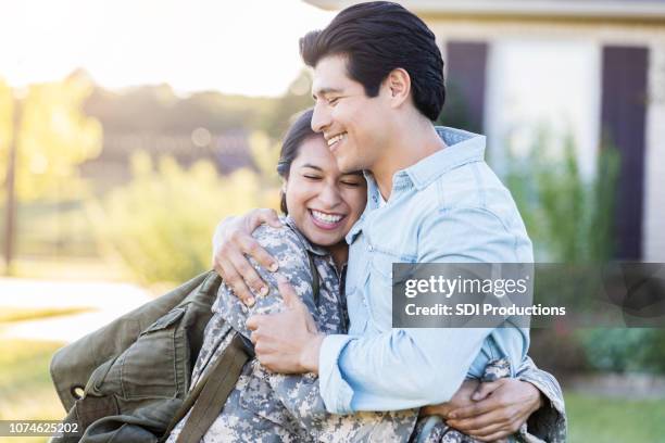 female in uniform shares a hug with her husband - married stock pictures, royalty-free photos & images