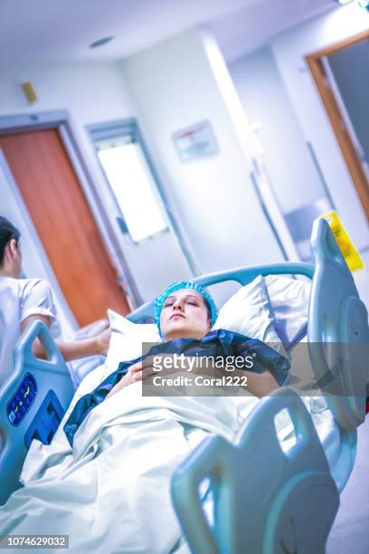 nurse wheeling patient in gurney through hospital corridor - hospital gurney stock pictures, royalty-free photos & images