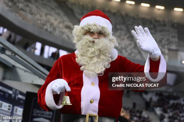 Man dressed as Santa Claus rings a bell on the pitch prior to the French L1 football match between Bordeaux and Amiens on December 23, 2018 at the...