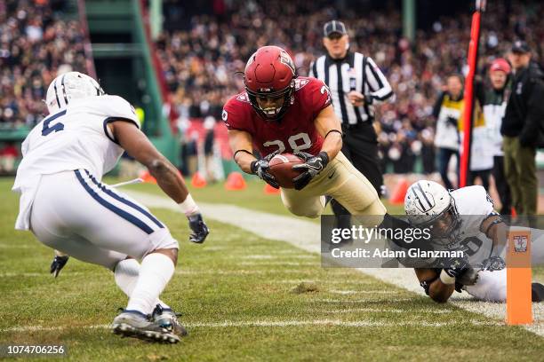 Henry Taylor of the Harvard Crimson scores a touchdown while being tackled by Noah Pope of the Yale Bulldogs in the second quarter of a game at...