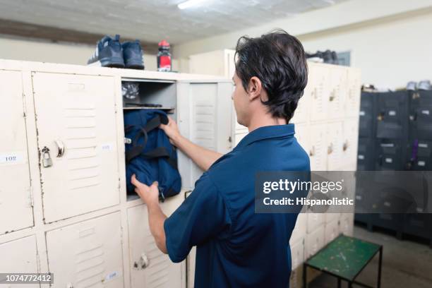 靴工場でのロッカー ルームで彼の服を片付けて、ブルーカラー労働者の backview - locker room ストックフォトと画像