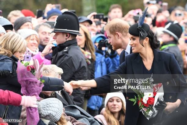 Meghan, Duchess of Sussex and Britain's Prince Harry, Duke of Sussex greet the crowds after the Royal Family's traditional Christmas Day service at...