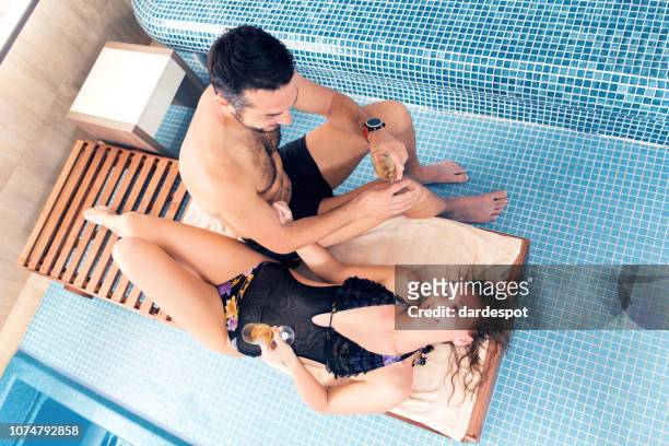 casal relaxante à beira da piscina - chaise longue - fotografias e filmes do acervo