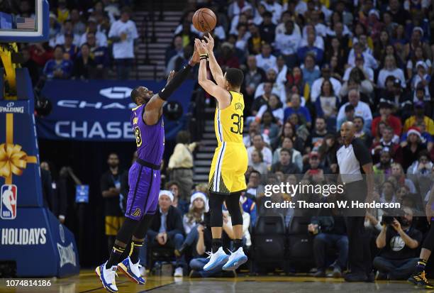 Stephen Curry of the Golden State Warriors shoots over LeBron James of the Los Angeles Lakers during the first half of their NBA Basketball game at...