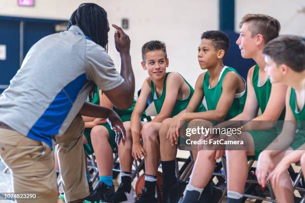 小学校の男子バスケット ボール チームの監督と副業のベンチに座って - exhibition match ストックフォトと画像