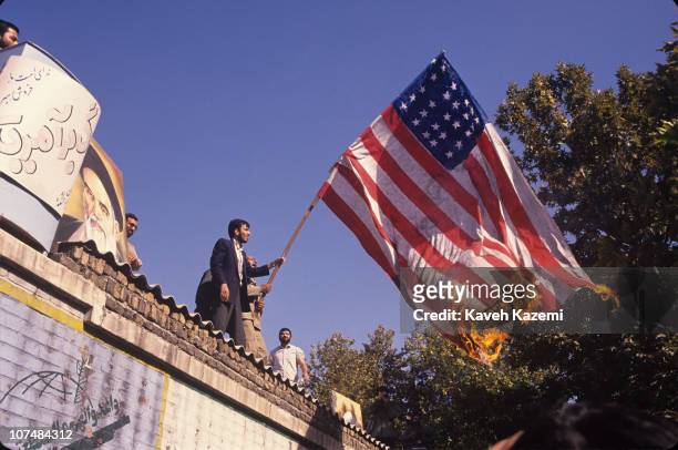 Iranian Revolutionary Guards burn a US flag on top of the walls of the former US embassy in Tehran, on the anniversary of its occupation by...