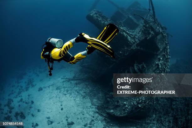 gelbe geeignet taucher erkunden eine überwucherte schiffswrack unter dem roten meer - shipwreck stock-fotos und bilder