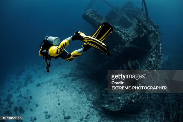 gul passar dykare utforskar en övervuxen skeppsbrott under röda havet - dykarutrustning bildbanksfoton och bilder