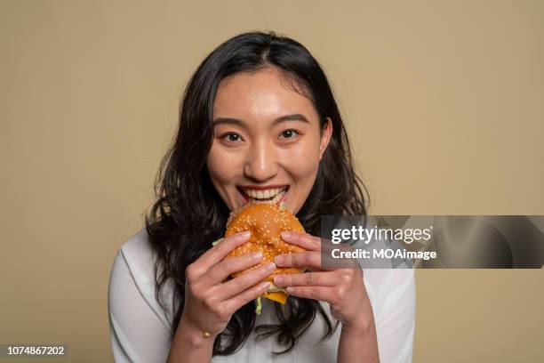 a young asian girl is eating - burger portrait photos et images de collection