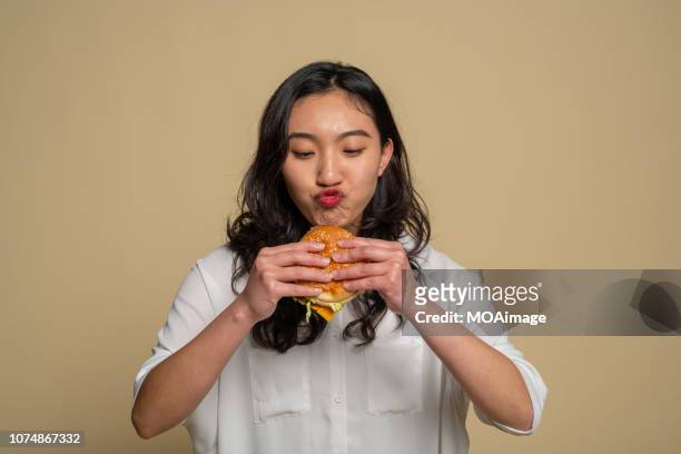 a young asian girl is eating - woman eating burger stock pictures, royalty-free photos & images