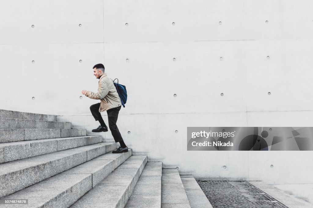 Young man running up steps in urban setting