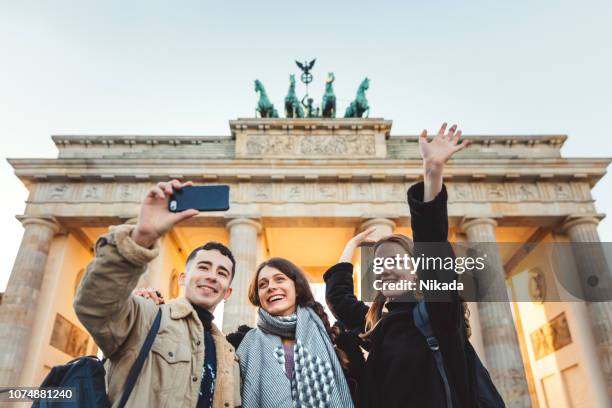 friends at brandeburg gate in berlin take a selfie - berlin tourist stock pictures, royalty-free photos & images