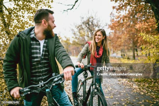 jeune couple gai, prendre un vélo ride dans le parc - 2018 cycling photos et images de collection