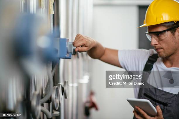 man using tablet at natural gas processing facility - meter stock pictures, royalty-free photos & images