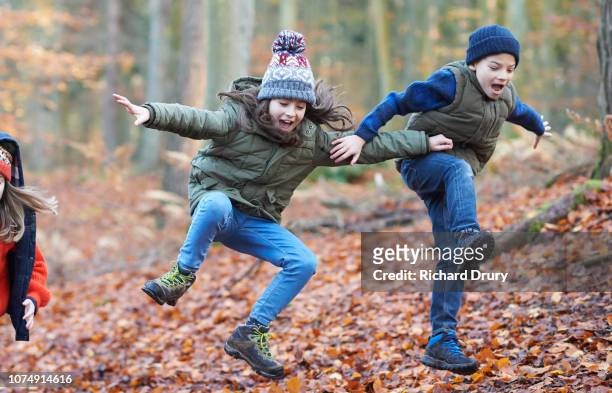 children jumping for joy in autumnal woodland - differential focus fotografías e imágenes de stock