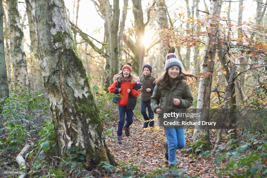 Children running along a path in Autumnal woodland