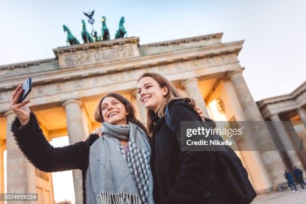 twee vrienden bij de brandenburger poort in berlijn nemen een selfie - berlin brandenburger tor stockfoto's en -beelden