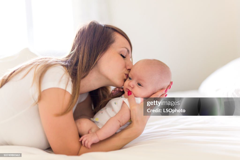 Portrait of mother with her 3 month old baby in bedroom