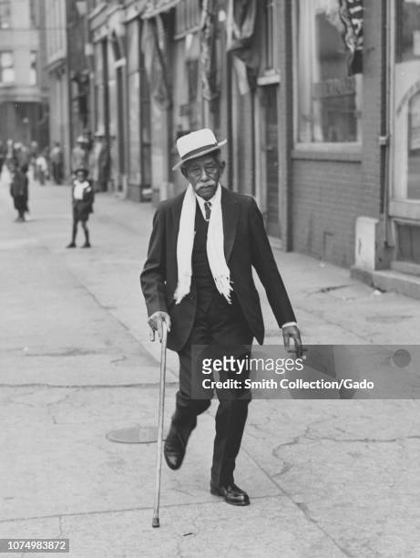 Photograph of an elderly African American man walking along the street on Easter morning, Chicago, Illinois, 1935. From the New York Public Library.