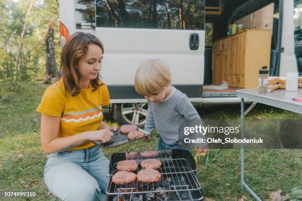 woman cooking burger on grill in forest with little boy - car grill stock pictures, royalty-free photos & images