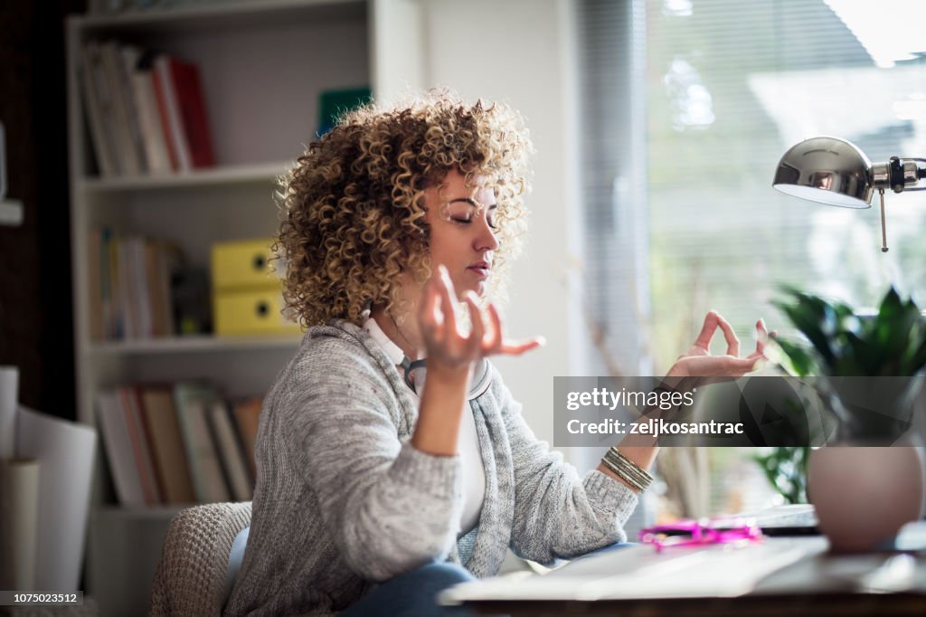Young businesswoman meditating in her office