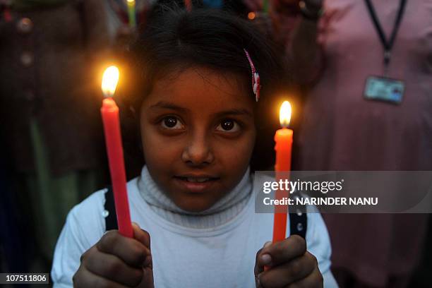 Young Indian girl with members of Akhil Bhartiya Human Rights organization holds lit candles at India-Pakistan Wagah Border in India on December 10,...