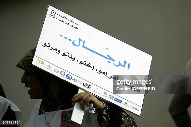 Lebanese woman carries a placard that reads in Arabic "A man cares about his mother, sister, daugher and wife" during a rally organized by KAFA, an...