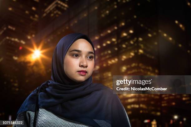 pensive serious muslim female looking away with urban background at night - muslim woman darkness stock pictures, royalty-free photos & images