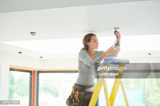 female electrician installing downlights - woman spotlight stock pictures, royalty-free photos & images