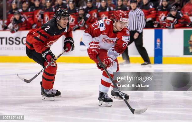 Phillip Schultz of Denmark skates in on goal as Evan Bouchard of Canada gives chase in Group A hockey action of the 2019 IIHF World Junior...