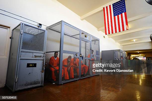 Inmates at Chino State Prison sit inside a metal cage in the hallway on December 10, 2010 in Chino, California. Inmates wait in the cages to be...