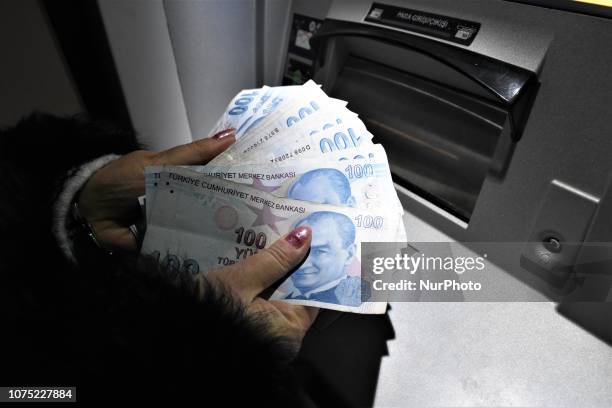 Woman holds Turkish lira banknotes in front of an ATM machine in Ankara, Turkey on December 27, 2018. A year is passed under economic difficulties as...