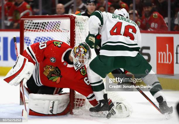 Collin Delia of the Chicago Blackhawks makes a stop against Jared Spurgeon of the Minnesota Wild at the United Center on December 27, 2018 in...