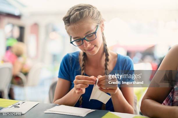tienermeisje ansichtkaarten stempels in briefkaarten steken in straat café in malcesine, italië - kleverig stockfoto's en -beelden