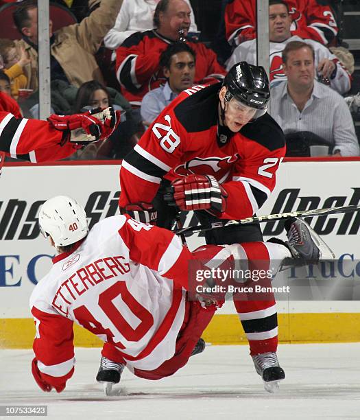 Henrik Zetterberg of the Detroit Red Wings is hit by Anton Volchenkov of the New Jersey Devils at the Prudential Center on December 11, 2010 in...