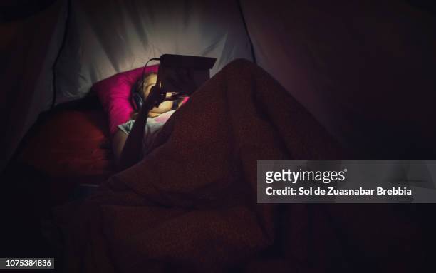 relaxed girl watching videos and listening to music on her digital tablet inside a tent - girl looking at computer foto e immagini stock