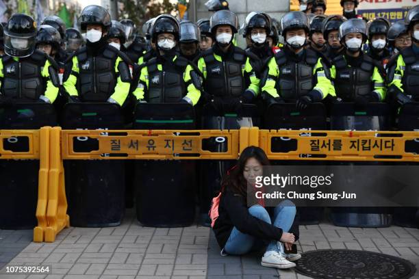 Woman sits in front of riot police blocking the road to protect protesters during the anti-government protest rally asking for the greater protection...