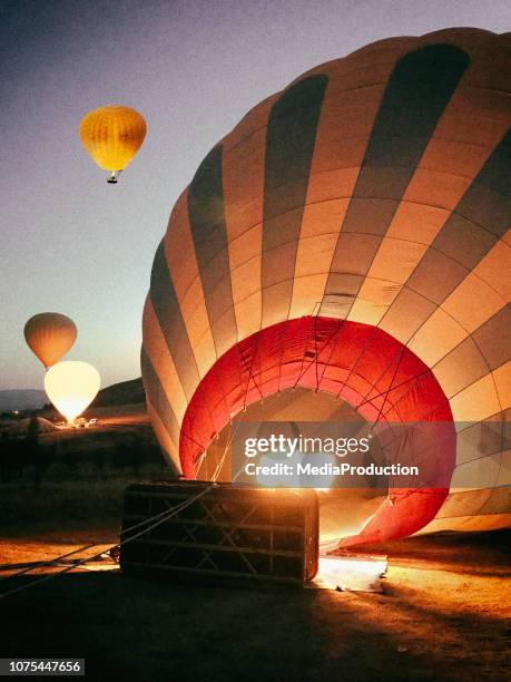 preparación de un globo de aire caliente al atardecer - inflar fotografías e imágenes de stock