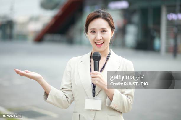 female reporter holding microphone - fernsehreporter stock-fotos und bilder