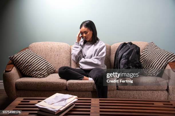 ein student des asiatischen erbes erleben finanziellen oder emotionalen stress zu hause in ihrer wohnung. - stressed young woman sitting on couch stock-fotos und bilder