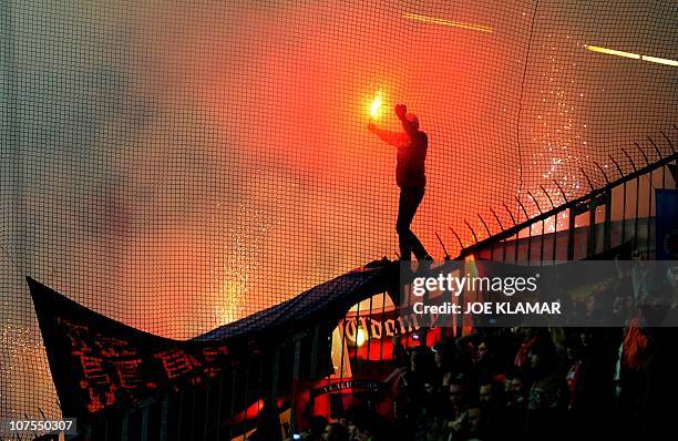 Spartak Moscow fan holds a flare as he walks on security fencing during the group F UEFA Champion's league match between MSK ZIlina and Spartak...