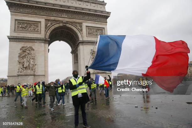 Protesters wearing Yellow Vests and holding a French flag near l'Arc de Triomphe on December 01, 2018 in Paris, France. The 'Yellow Vest' is a...