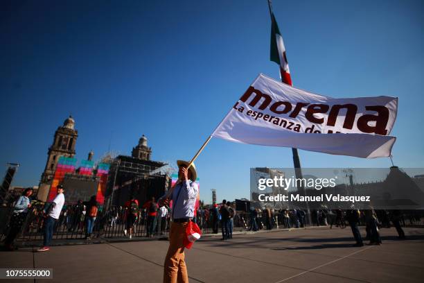 Man waves a flag of Morena party prior to the events of the Presidential Investiture as part of the 65th Mexico Presidential Inauguration at Zocalo...