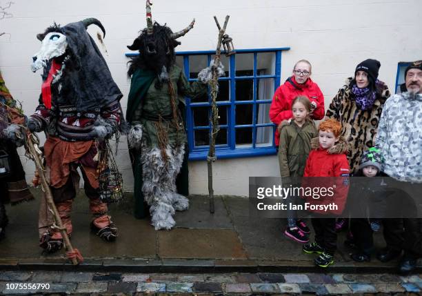 Family react as they stand next to participants during the annual Whitby Krampus parade on December 01, 2018 in Whitby, England. The Krampus is a...