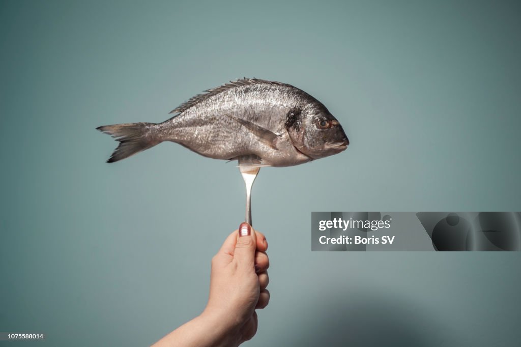Woman holding fish on fork