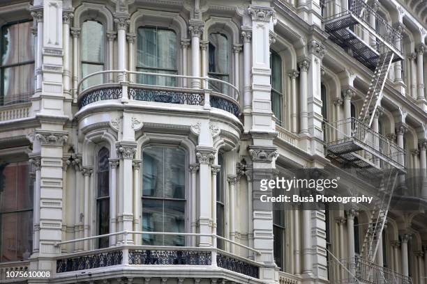 bay window of typical cast iron building with fire escapes in chelsea, new york city - chelsea new york stock-fotos und bilder